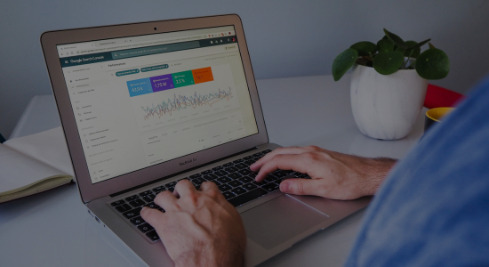Blog post landing page image and link - A person using Search Console on their laptop, sitting at their work desk, with a small plant also on the desk.